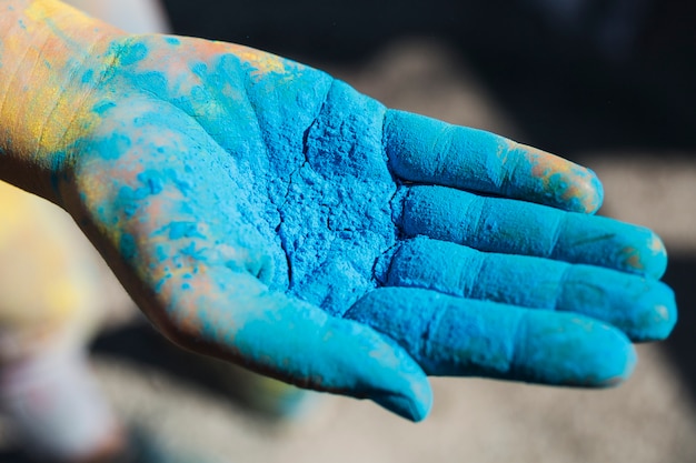 Nahaufnahme der Hand einer Person, die blaue holi Farbe anhält