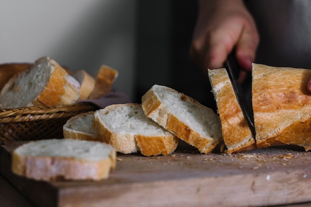 Nahaufnahme der Hand eines Bäckers, die Laib des frischen Brotes schneidet