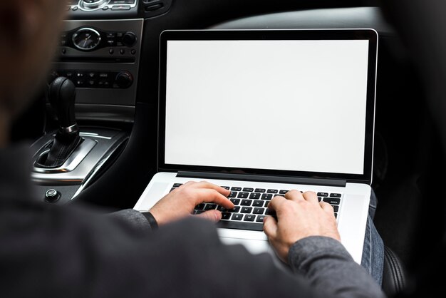 Nahaufnahme der Hand eines Geschäftsmannes unter Verwendung des Laptops, der im Auto sitzt