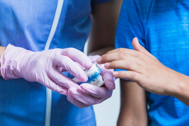 Nahaufnahme der Hand eines Jungen, die Zahnputzformgriff vom Zahnarzt berührt