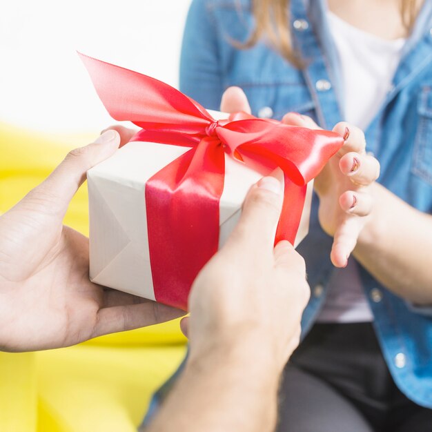 Nahaufnahme der Hand eines Mannes, die seiner Frau Geschenk gibt