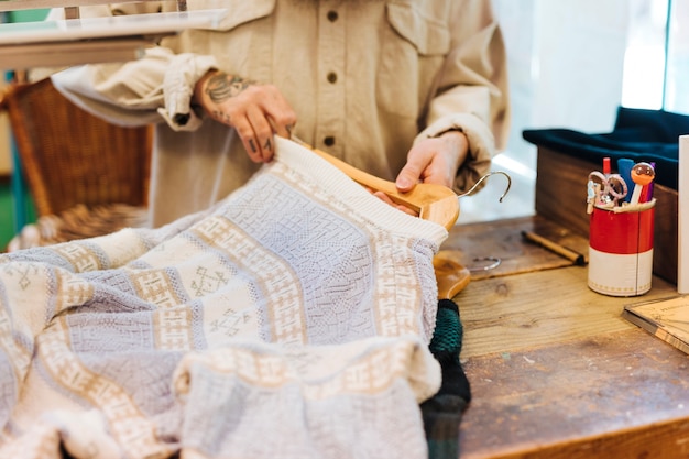 Nahaufnahme der Hand eines Mannes, welche die Kleidung auf dem Aufhänger im Shop vereinbart