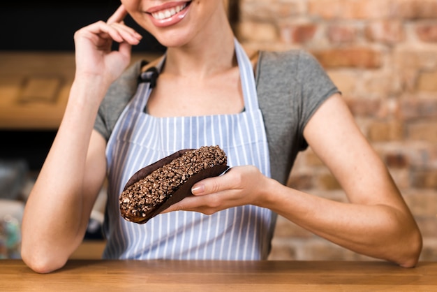 Nahaufnahme der Hand eines weiblichen Bäckers, die köstliche Eclairs hält