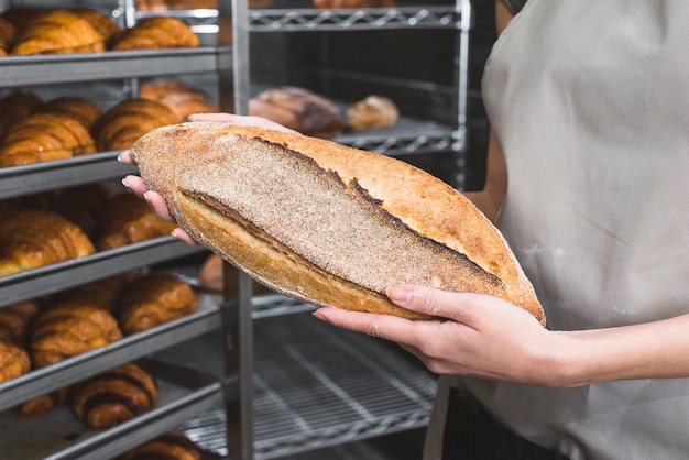 Nahaufnahme der Hand eines weiblichen Bäckers, die Vollweizenbrotlaib hält