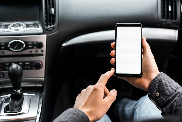 Nahaufnahme der Hand unter Verwendung des Smartphone mit dem weißen Bildschirm, der im Auto sitzt