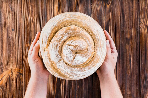 Nahaufnahme der Hand Wirbel halten gebackenes Brötchen