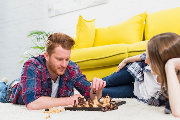 Nahaufnahme der jungen Frau den Mann betrachtend, der das Schachspiel spielt