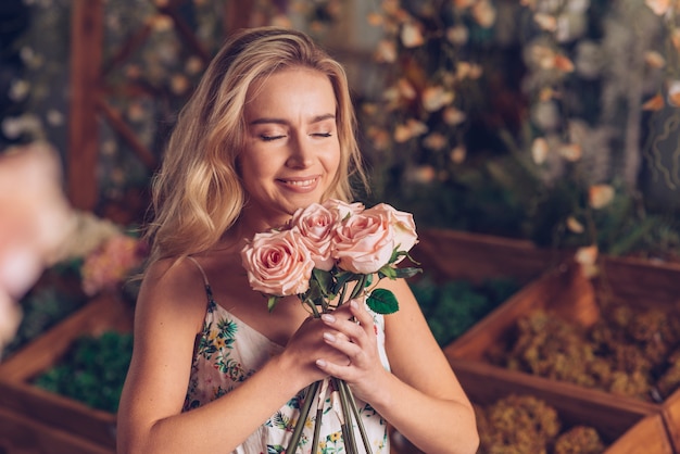 Kostenloses Foto nahaufnahme der jungen frau die rosafarbenen rosen riechend