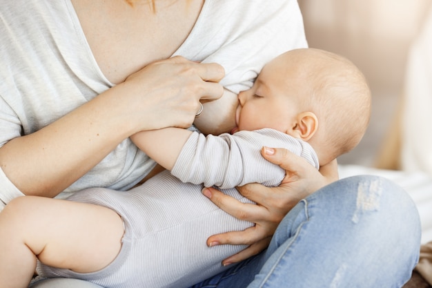 Kostenloses Foto nahaufnahme der jungen mutter, die ihr kleines kind stillt. berührende szene der mutterschaftsliebe und fürsorge. familien-, mutterschafts- und lebensstilkonzept.