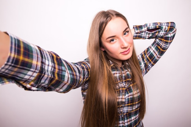 Nahaufnahme der jungen schönen Frau, die selfie nimmt. Isolierte weiße Wand