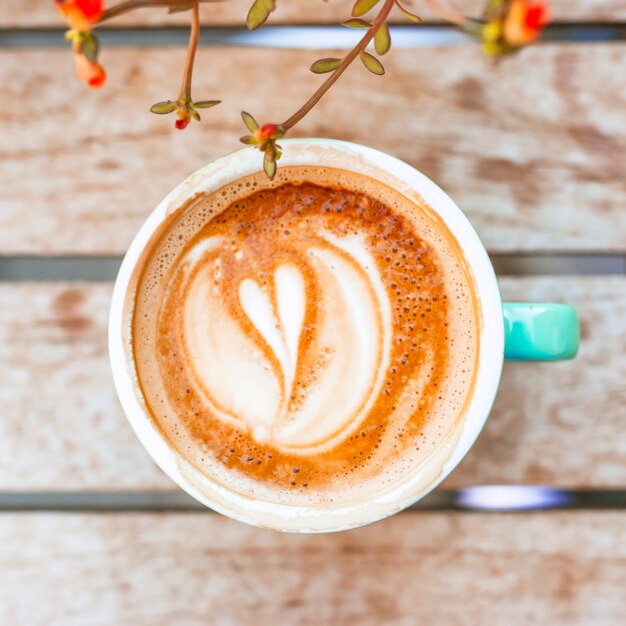 Nahaufnahme der Kaffeetasse mit Herzform Lattekunst auf hölzerner Tabelle