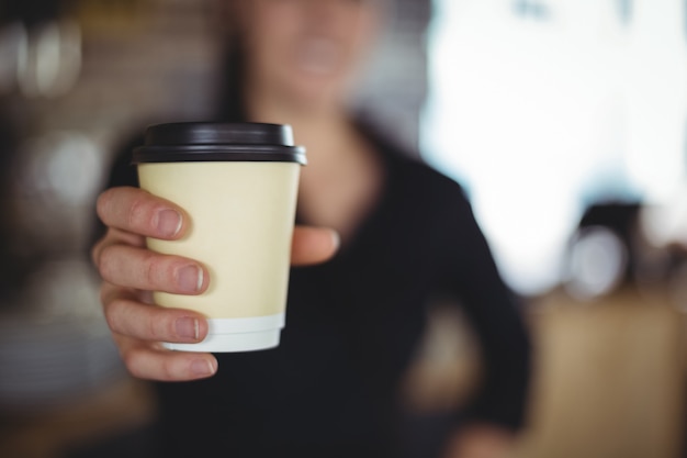 Nahaufnahme der kellnerin stehend mit wegwerfkaffeetasse