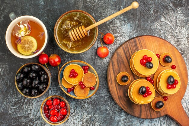 Nahaufnahme der klassischen Pfannkuchen auf Schneidebrett mit Honig und Früchten