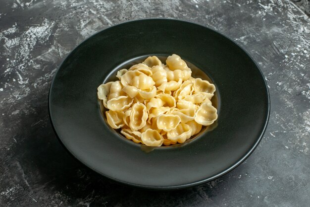 Nahaufnahme der köstlichen Conchiglie auf einem schwarzen Teller auf grauem Hintergrund