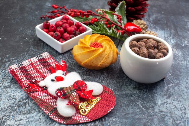Nahaufnahme der köstlichen Keksdekorationszubehör Weihnachtssocke und Cornell in einer Schüssel Tannenzweigen auf dunkler Oberfläche