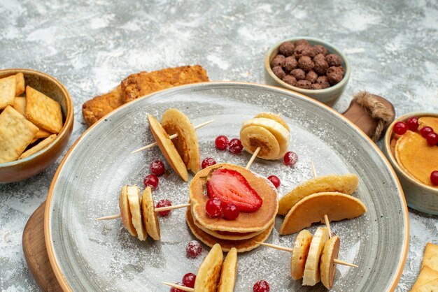 Nahaufnahme der köstlichen Pfannkuchenplätzchen und -kuchen zum Frühstück auf Schneidebrett auf Blau