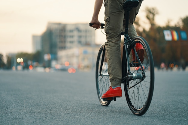Nahaufnahme der lässigen Mannbeine, die klassisches Fahrrad auf Stadtstraße fahren