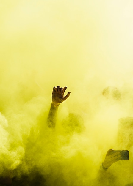Nahaufnahme der Leute tanzen und in der gelben Explosion der holi Farbe
