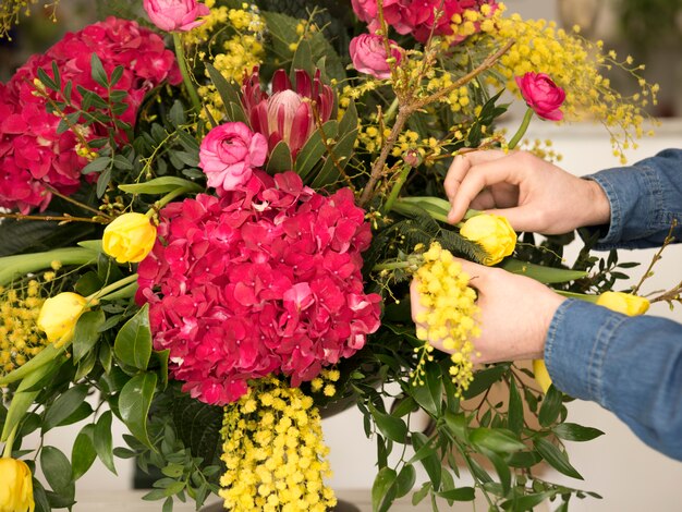 Nahaufnahme der männlichen Floristenhand, welche die Blumen im Vase anordnet