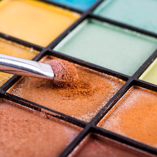 Nahaufnahme der Make-upbürste mit Palette der bunten Lidschatten