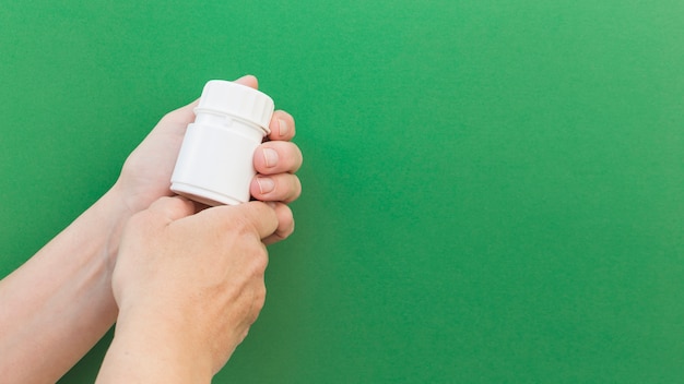 Kostenloses Foto nahaufnahme der pillenplastikflasche der hand gegen grünen hintergrund