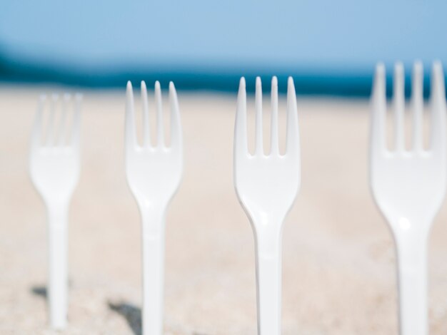 Nahaufnahme der Plastikgabeln fest im Sand auf dem Strand