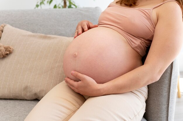 Nahaufnahme der schwangeren Frau, die auf der Couch sitzt