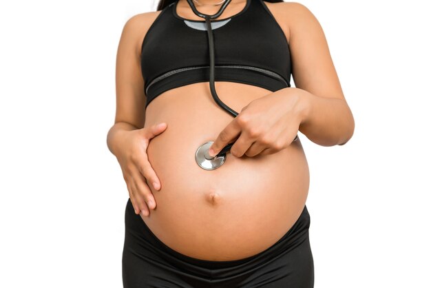 Nahaufnahme der schwangeren Frau mit Stethoskop auf Bauch, der das Baby hört
