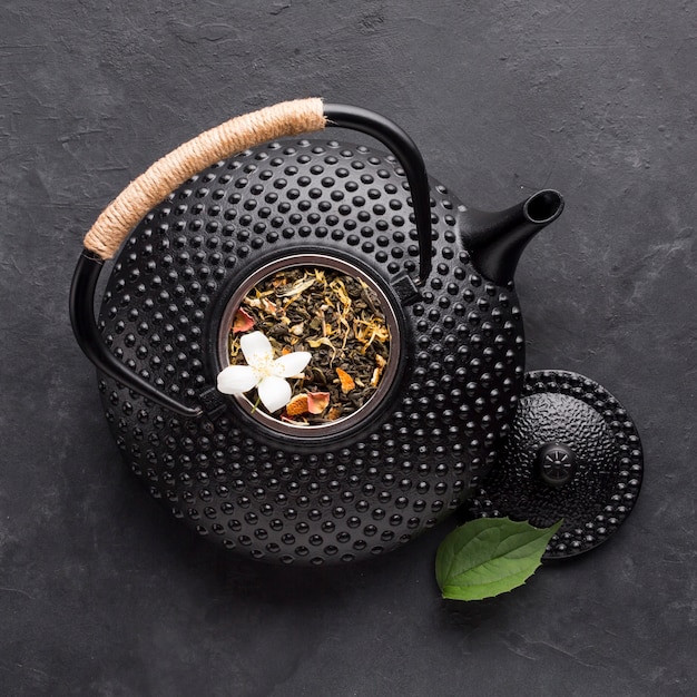 Nahaufnahme der schwarzen Teekanne mit getrocknetem Teekraut