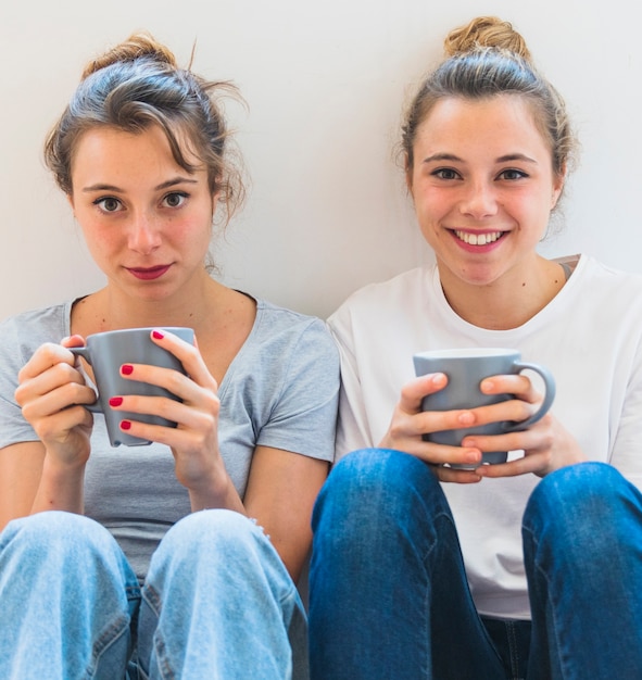 Kostenloses Foto nahaufnahme der schwester zwei, die graue kaffeetasse hält