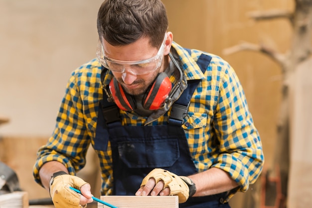 Kostenloses Foto nahaufnahme der tragenden sicherheitsgläser eines männlichen tischlers, die in der werkstatt arbeiten