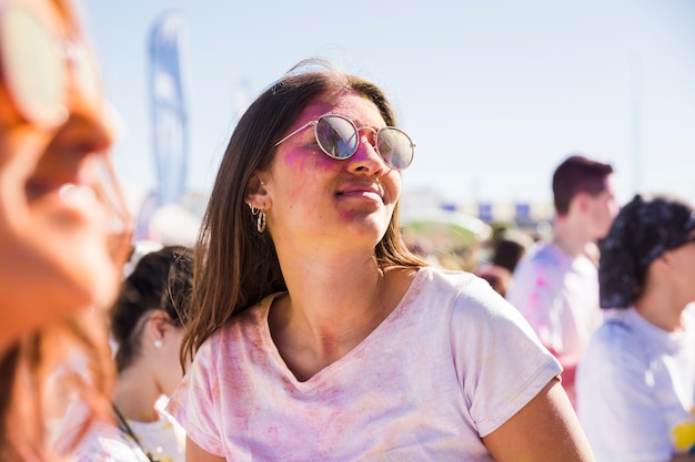 Kostenloses Foto nahaufnahme der tragenden sonnenbrille der frau, die mit holi farbe spielt