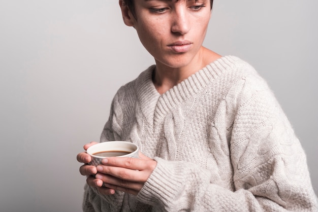 Nahaufnahme der tragenden strickjacke der jungen frau, die kaffeetasse hält