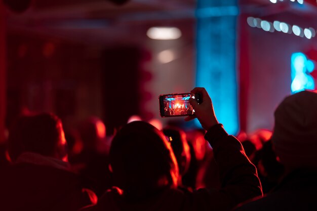 Nahaufnahme der Videoaufnahme mit Smartphone während eines Konzerts. Getöntes Bild