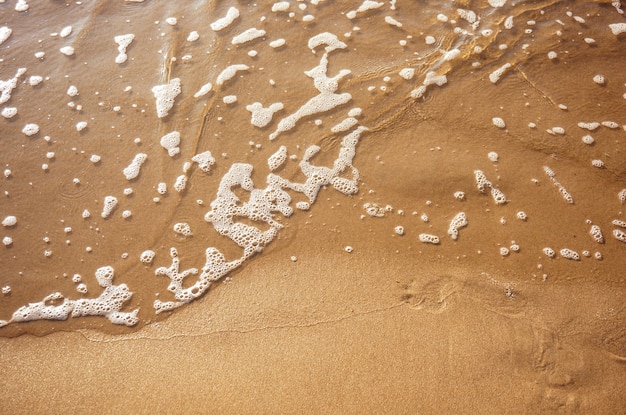 Nahaufnahme der Wassertextur auf dem Sand, kleine Bläschen auf der Oberfläche