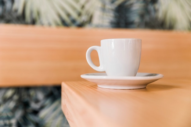 Nahaufnahme der weißen Kaffeetasse auf hölzernem Schreibtisch in cafÃ?
