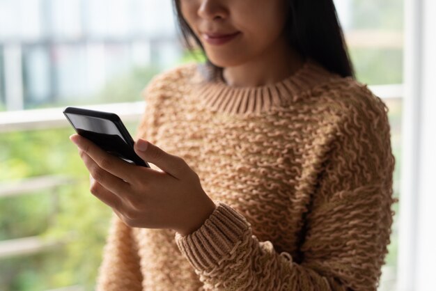 Nahaufnahme der zufriedenen Dame in der Strickjacke Online-Artikel lesend