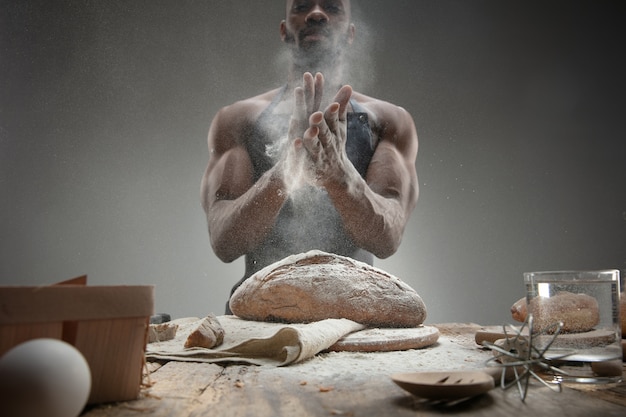 Nahaufnahme des afroamerikanischen Mannes kocht frisches Müsli, Brot, Kleie auf Holztisch. Leckeres Essen, Ernährung, Bastelprodukt. Glutenfreie Lebensmittel, gesunde Lebensweise, biologische und sichere Herstellung. Handgemacht.