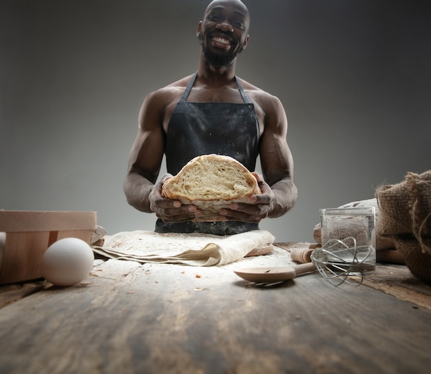 Nahaufnahme des afroamerikanischen Mannes kocht frisches Müsli, Brot, Kleie auf Holztisch. Leckeres Essen, Ernährung, Handwerksprodukt. Glutenfreie Lebensmittel, gesunde Lebensweise, biologische und sichere Herstellung. Handgemacht.