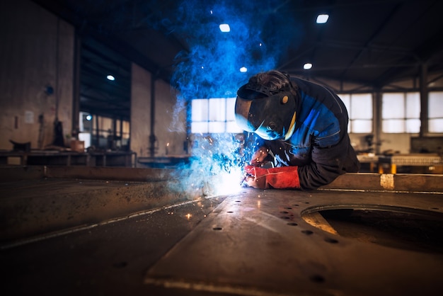 Nahaufnahme des Arbeiters, der Metallkonstruktion in industrieller Werkstatt schweißt