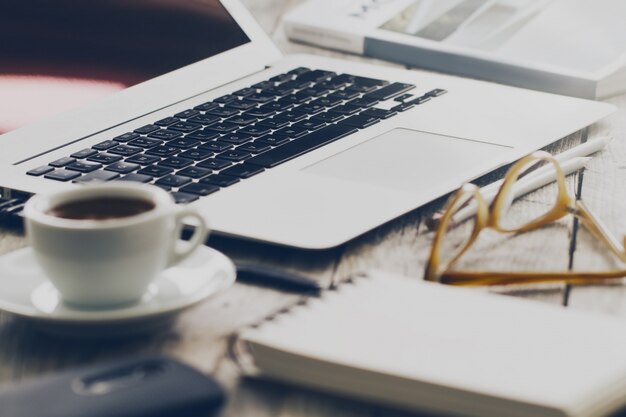 Nahaufnahme des Arbeitsbereichs mit modernen kreativen Laptop, Tasse Kaffee und Bleistifte. Horizontal mit Kopierraum.