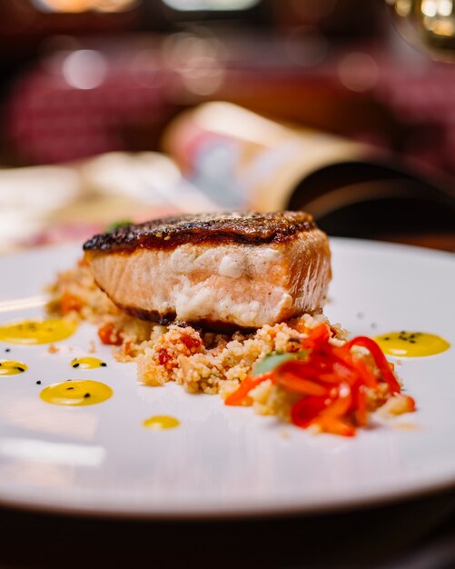 Nahaufnahme des gegrillten Fischfilets, das oben auf dem Couscous-Salat mit Paprika serviert wird