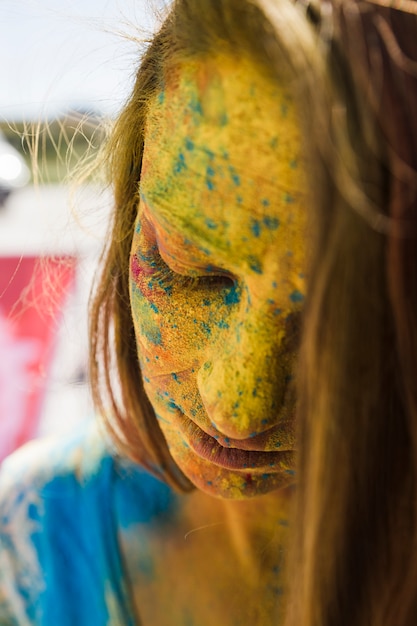 Nahaufnahme des Gesichtes der Frau bedeckt mit gelber holi Farbe