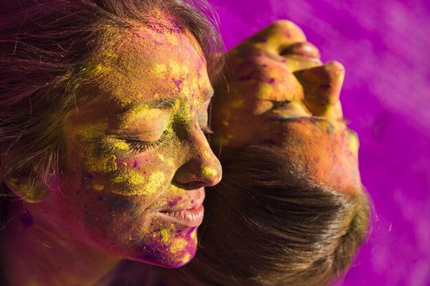 Nahaufnahme des Gesichtes der Frauen bedeckt mit mehrfarbiger holi Farbe