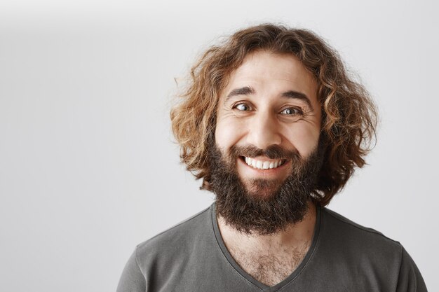 Nahaufnahme des glücklichen lächelnden nahöstlichen Mannes mit langem Bart und lockiger Frisur