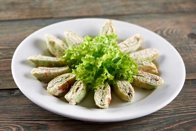 Nahaufnahme des großen weißen Tellers, serviert mit Häuschen-Gemüse-Mischung und dekoriert mit Salatblättern. Gute Vorspeise für leichten Alkohol oder Restaurant Catering.