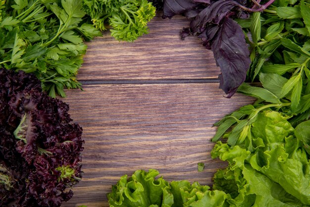Nahaufnahme des grünen Gemüses als Koriander-Minz-Salat-Basilikum auf Holztisch mit Kopienraum