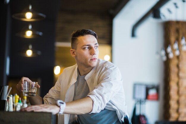 Nahaufnahme des jungen Mannes Glas Whisky in der Stange halten