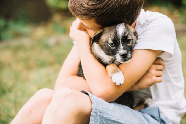 Nahaufnahme des Jungen seinen reizenden Welpen umfassend