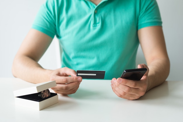 Nahaufnahme des Käufers Kreditkarte und Smartphone halten